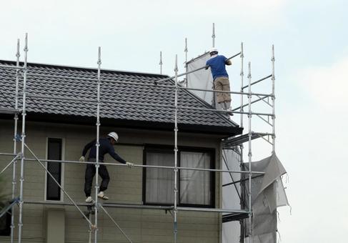 足場から外壁を塗装する作業風景