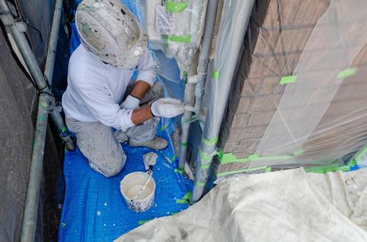 養生を施した狭い場所で塗装準備をする作業者